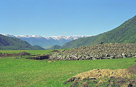 
La tombe d'un prince scythe (Kazakhstan), vallée de la Bukhtarma. Au printemps, si l'on porte le regard vers l'ouest, au-delà d'un défilé de la Bukhtarma, on peut voir la ligne de crêtes enneigées des monts Tarbagatay qui forment la frontière avec la RPC. Au premier plan, le kourgane en pierre (23 m de diamètre), dégagé sur son pourtour. En son centre, la fouille est couverte d'une protection en charpente de bois et bâche
