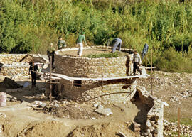 
Reconstitution de l'habitat néolithique à Khirokitia (Chypre). L'armature de bois est ensuite couverte de deux lits croisés de feuilles de cannes provenant des berges de la rivière. Elles ont été coupées fraîches, il est toutefois préférable, au dire des maçons, de les couper en hiver quand elles sont sèches
